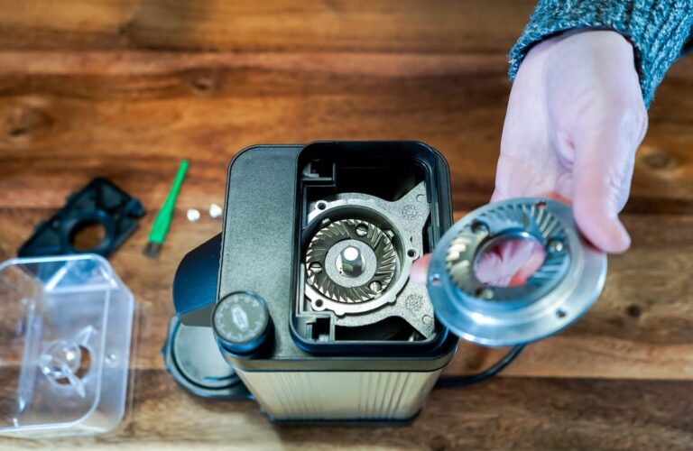 Home A disassembled coffee grinder with cleaning tools on a clean kitchen countertop.