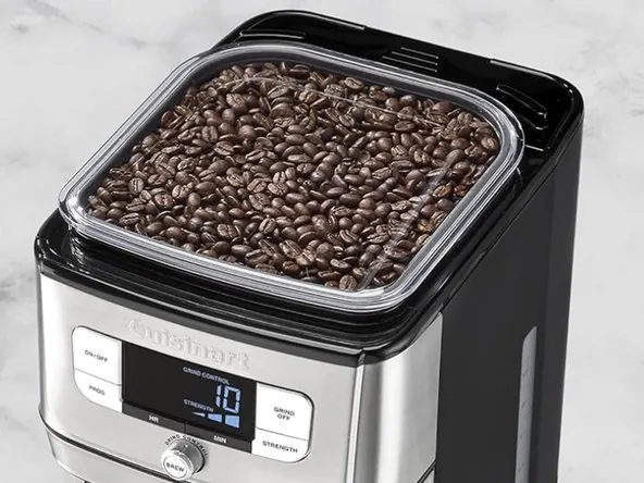 How to Clean a Cuisinart Coffee Grinder: Simple Routine A person carefully brushing loose coffee grounds from a coffee grinder chute.